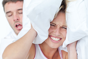 Woman trying to sleep while a man is snoring